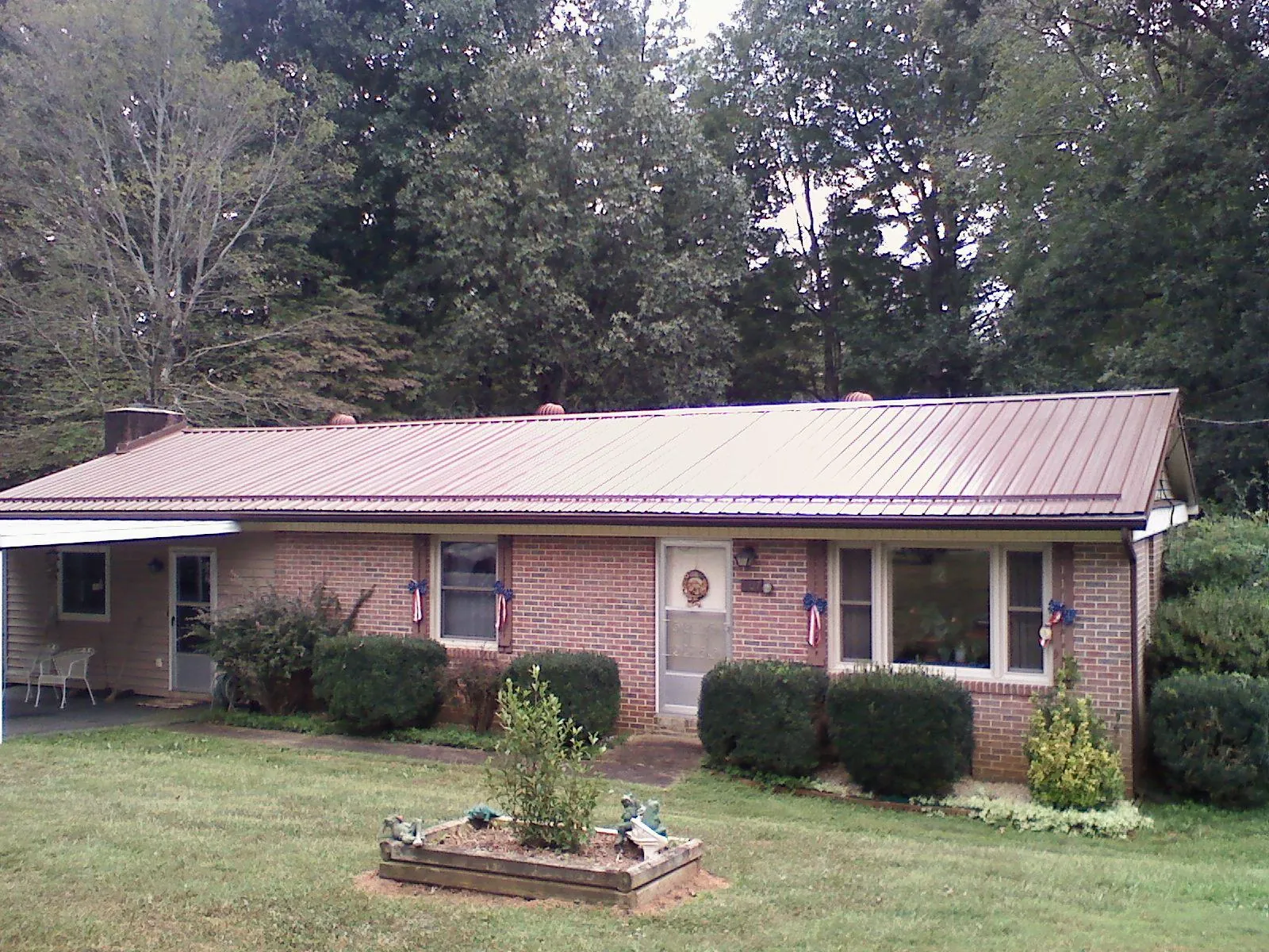 Bronze metal roof on a brick ranch home with a carport in Orrick