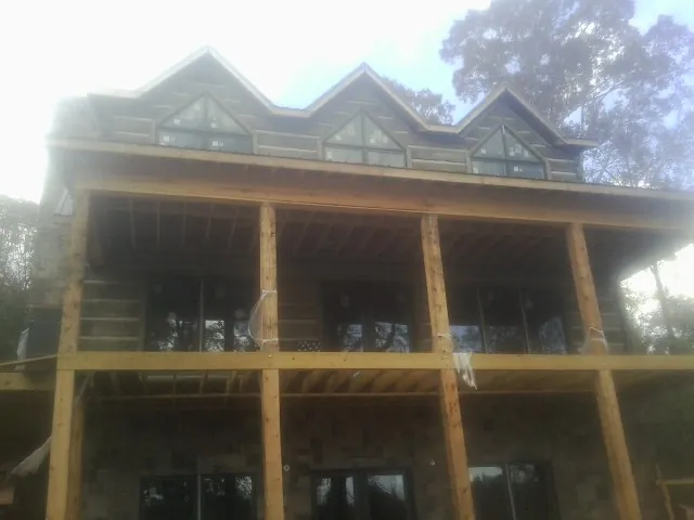 Dormers and porch framing on a large log home under construction — Roof Coating work by our crew in Orrick