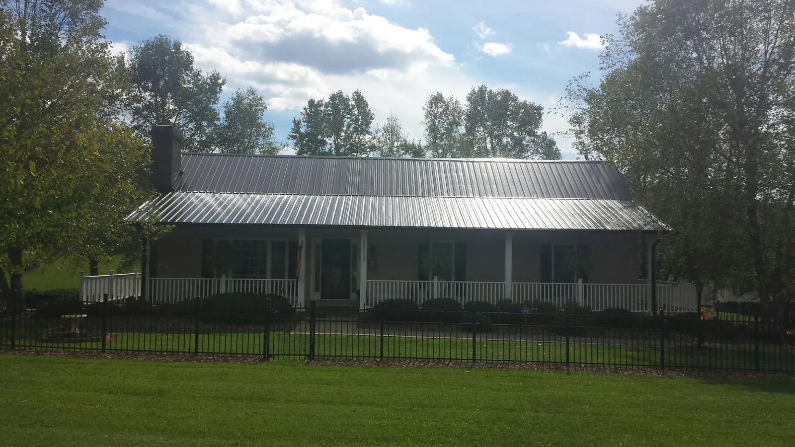 Gray metal roof on a brick ranch with a full width front porch — Gutter Guard Installation work by our crew in Orrick